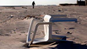 MEDIO AMBIENTE SILLA PLASTICA TUMBADA EN ARENA